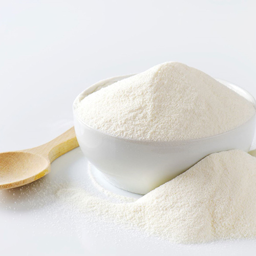 Close up of milk powder in a white bowl with a wooden spoon on the side