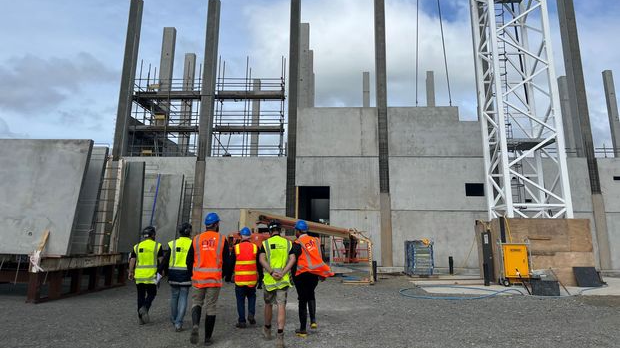 Group of people photpgrapohed from behind walking toward a construction site 