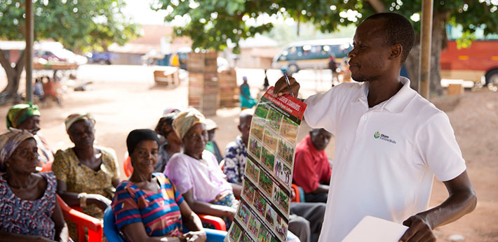 Man holding up a poster in front of group of female farm workers