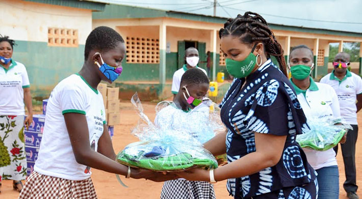 Woman handing over package to young girl at rural school