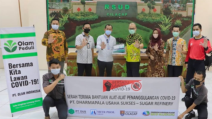 Group photo of Indonesian men and one woman wearing masks and holding up a banner