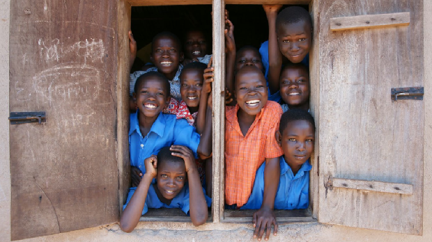 Smiling children photogaphed standing by a window frame at school