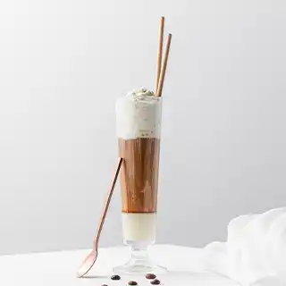 Tall glass filled with coffee, topped with cream