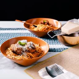 Two plates of pasta topped with meatballs