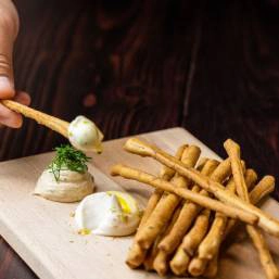 A person dipping a breadstick into cream and onion dip