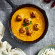 Orange creamy sauce with meatballs, served in a cast iron dish