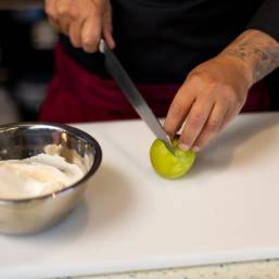 A chef cutting into a lime