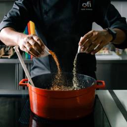 A chef sprinkling two types of seasoning over food