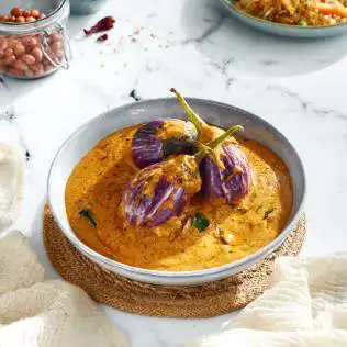 Plated Indian dish, baigan ka salan, a creamy yellow gravy topped with three small eggplants