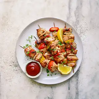 A plate filled with meat and vegetables on skewers