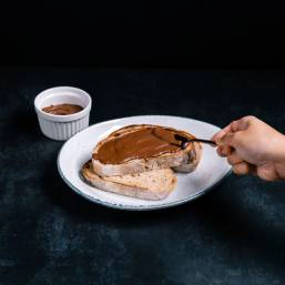 A person spreading chocolate spread on a slice of bread