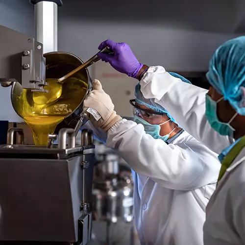 lab technicians pouring liquid substance into a mixer