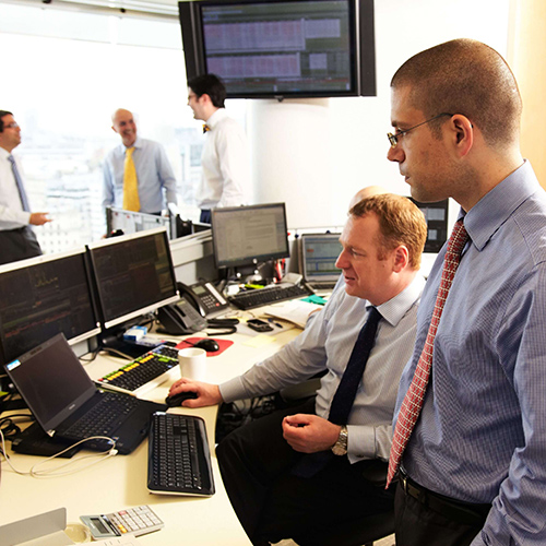 Two men in formal attire looking at a computer