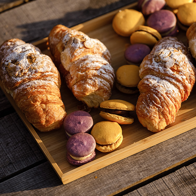 Styled wooden plate filled with croissants and macaroons