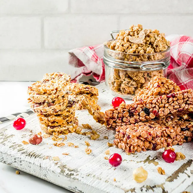 Styled shot of nut bars stacked on top of each other garnished with red berries