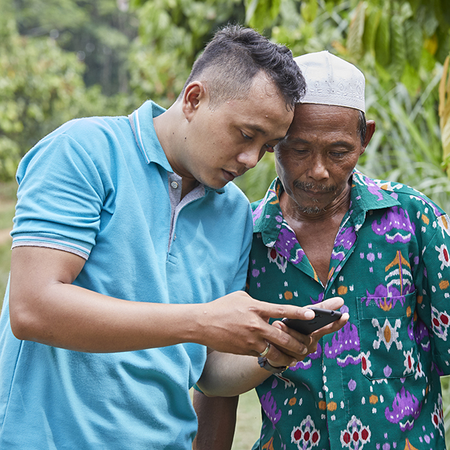 Two men standing next to each other looking at a mobile device