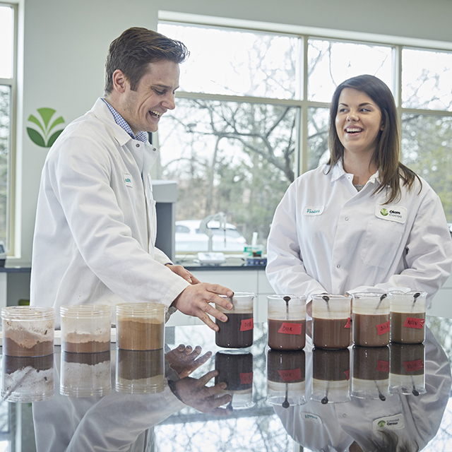 Two people smiling and looking at red cascara samples