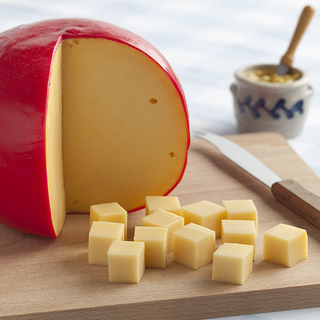 Close up shot of a  wheel of edam cheese cut into small blocks
