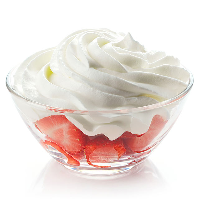Close up shot of a bowl of strawberries topped with cream