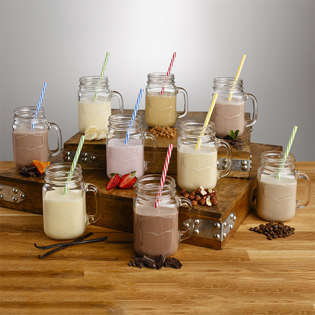 Different flavors of diary beverages in mason jars and straws displayed on a wooden table