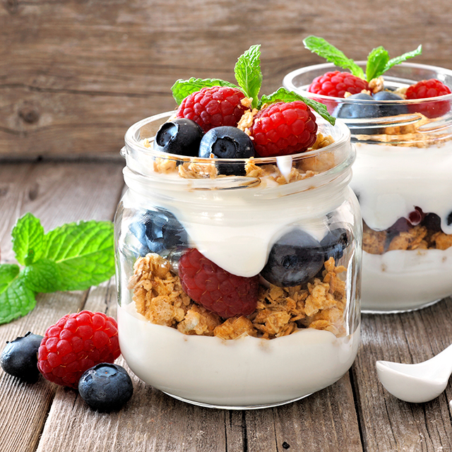 Close up shot of a mason jar filled with yogurt, berries and muesli