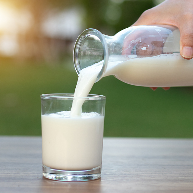 Person pouring pasteurized milk in a glass
