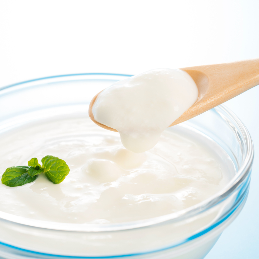 Close up shot of yogurt being scooped with a wooden spoon out of a bowl 