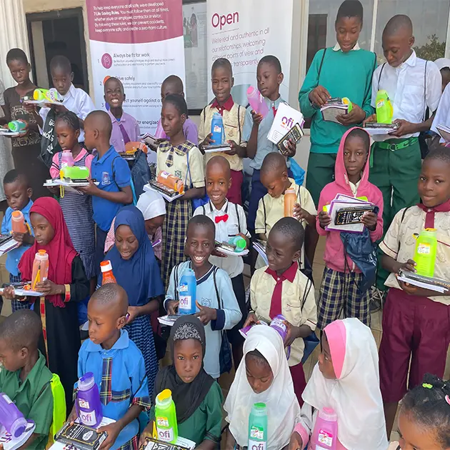 A group of kids holding gifts from ofi, such as water bottles and books