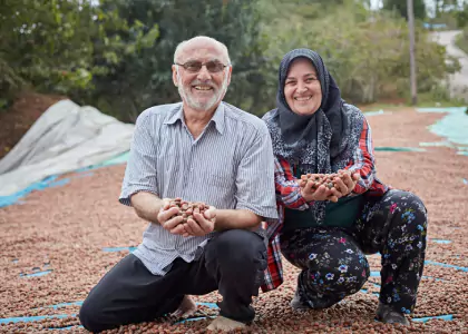 A man and a woman holding a handful of hazelnuts and smiling
