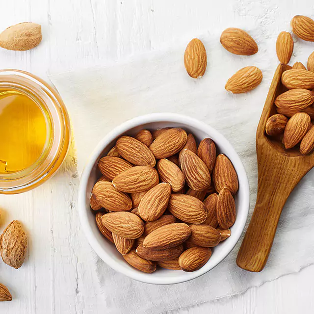 A cup of almonds next to oil