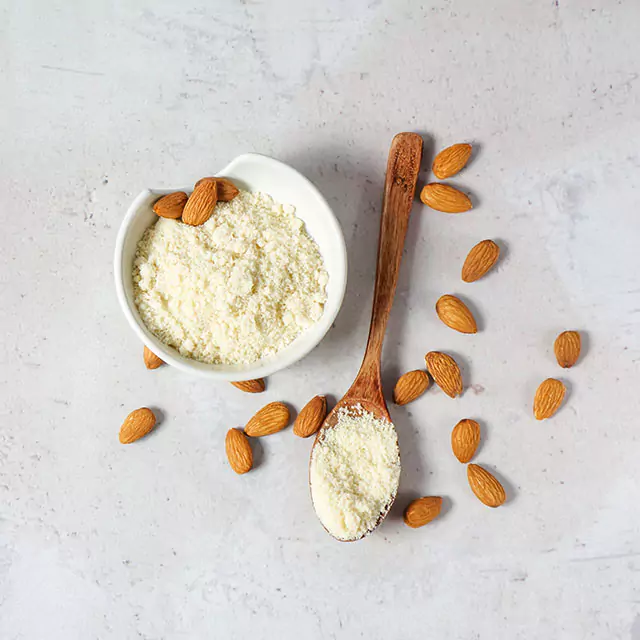 Almonds spread around the bowl filled with almond flour