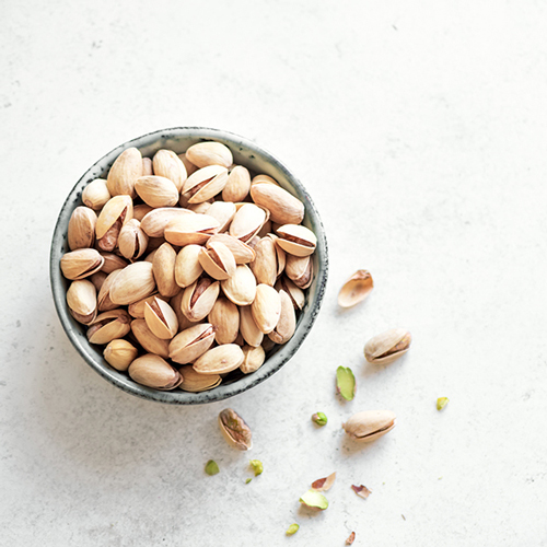 Close up shot of roasted pistachios in small bowl