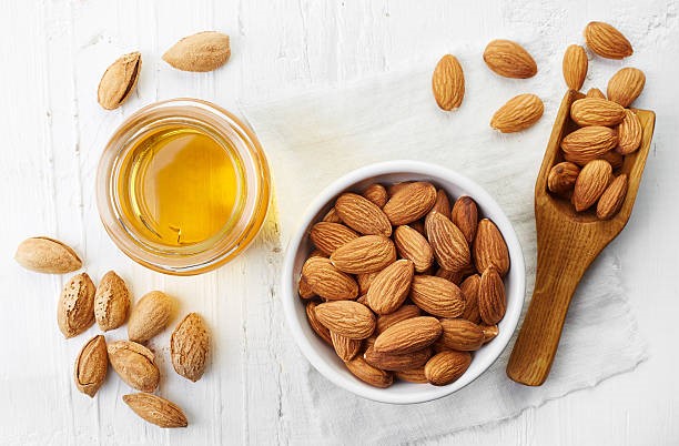 Above shot of almonds in a bowl and almond oil on the side