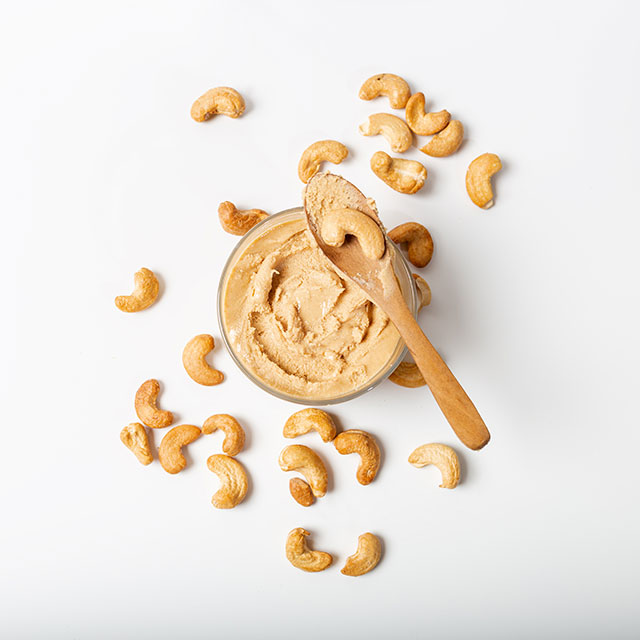 Above shot of cashew nut butter paste with raw cashews scattered on the side 