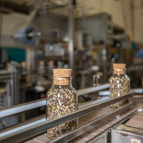 Pepper kernels in a glass bottle on a conveyer belt