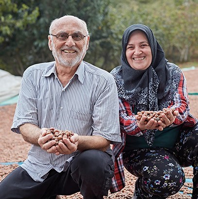 A man and a woman holding cocoa seeds in their handpalms