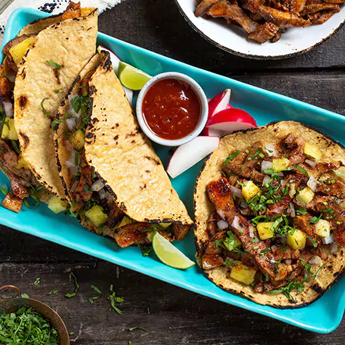 Close up shot of Mexican tortillas with diced onions, herbs and pineapple on the side