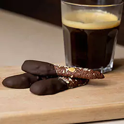 A cup of black coffee with three chocolate desserts