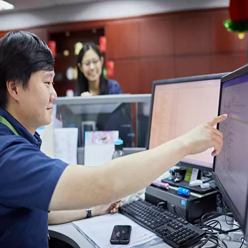 Male worker sitting behind a desk and pointing to something on his computer