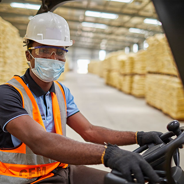 Male worker wearing a face mask sitting on a forklift in a warehouse