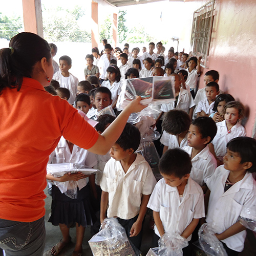 Female teacher handing out goodies to children at a school