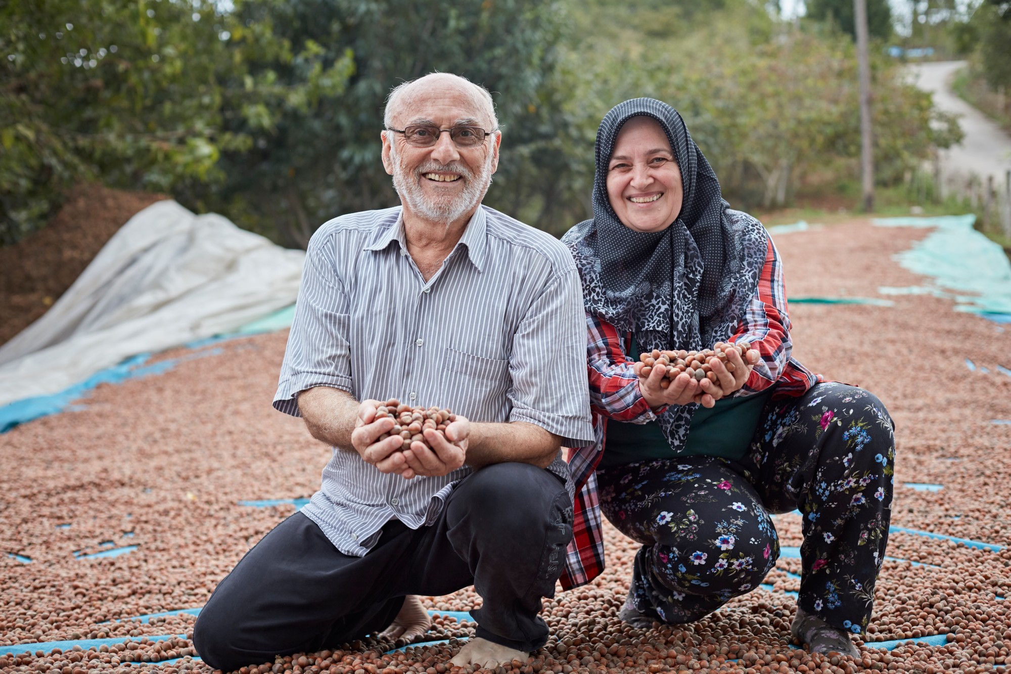 Two people kneeling and holding seeds in their hand