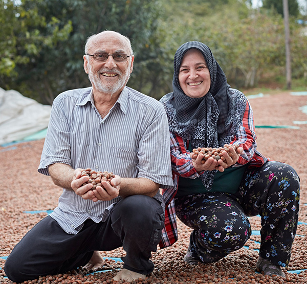 Two people kneeling and holding seeds in their hand