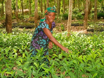 Candid image of a woman standing between green leafy plants